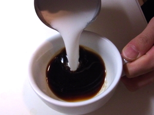 カップの中心にミルクを注ぎ始める様子